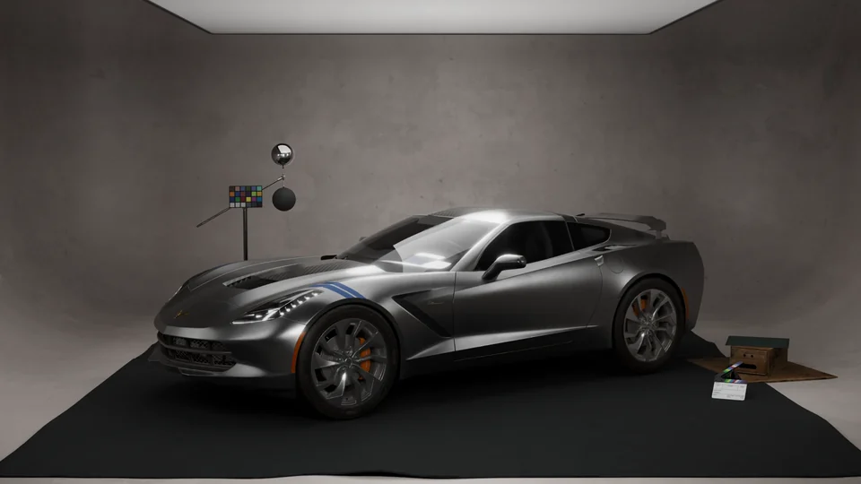 A grey sports car with a blue stripe and orange brake calipers in a studio