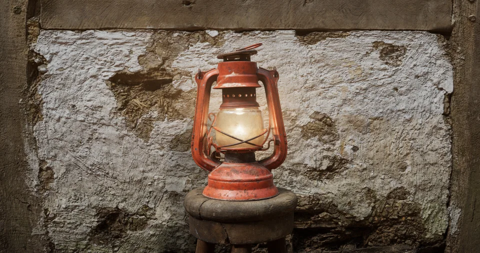 The red kerosene lantern glowing on a wooden stool
